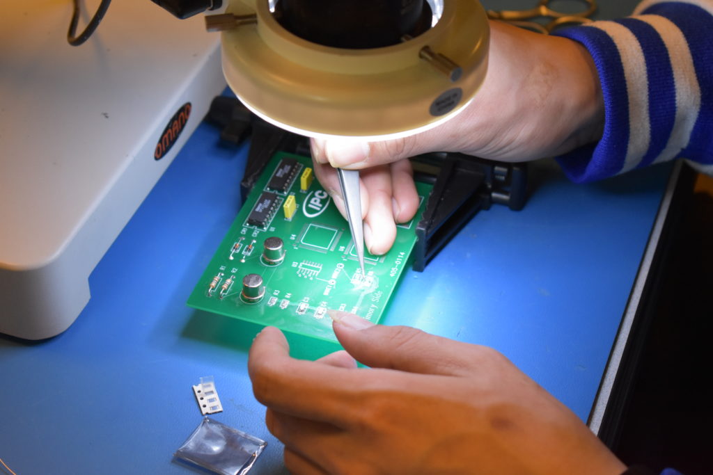 A participant working on a soldering board